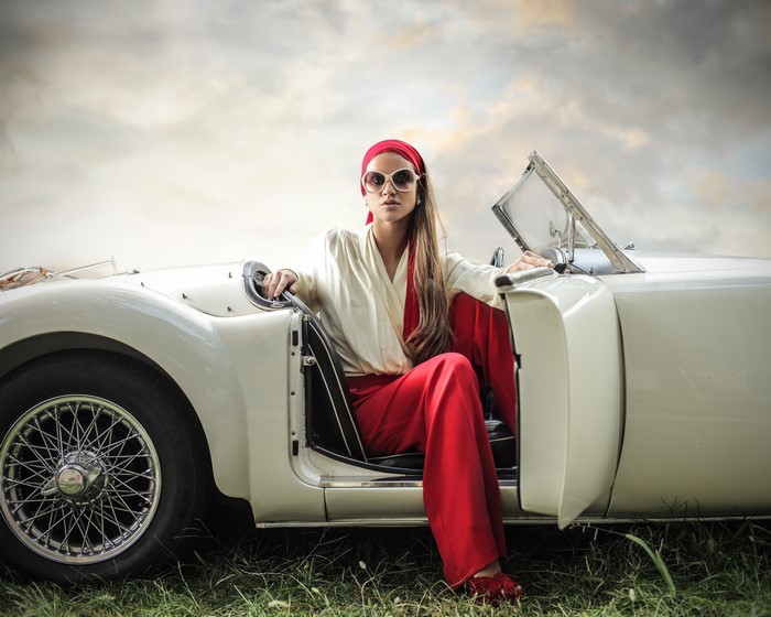Woman in red pants and white shirt in a convertible