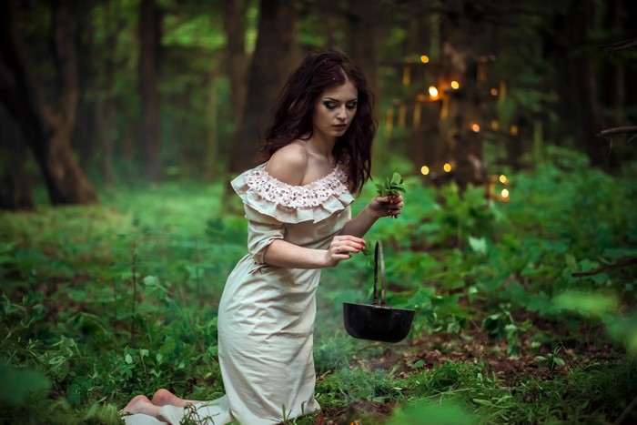 Woman in a dress in a forest with a cauldron