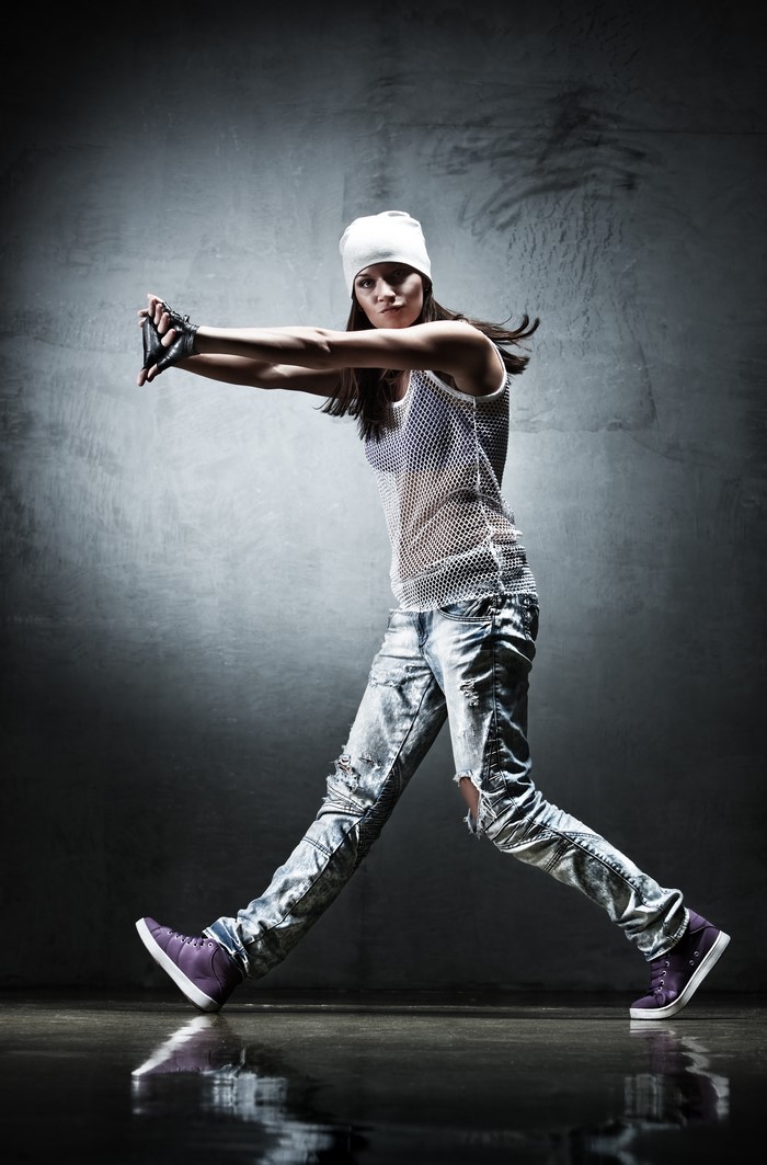 Woman in ripped jeans and white hat dancing