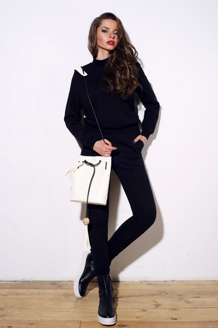 Woman in black tracksuit with white handbag