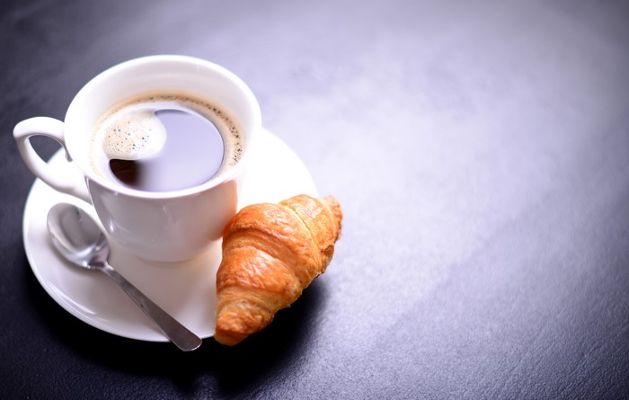Coffee cup with croissant and spoon