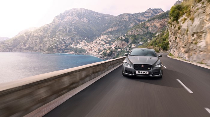 Grey Jaguar XJ driving on a coastal road