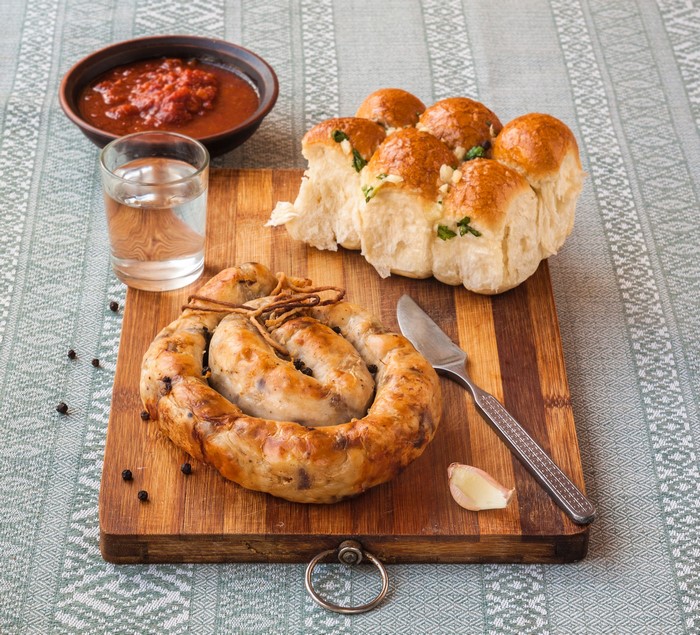 Sausage, Buns, Shot Glass, and Ketchup on Cutting Board