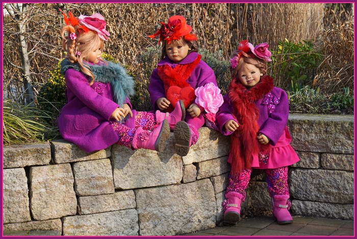 Three dolls in purple coats and hats in a park