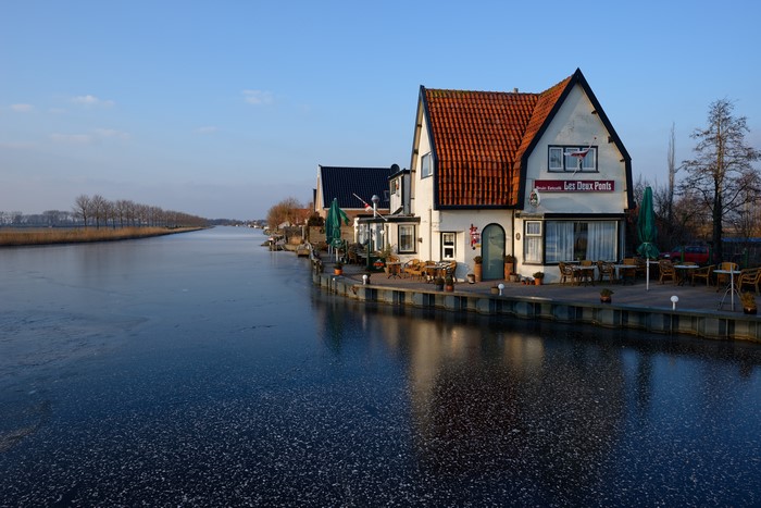Cafe Les Deux Ponts on a frozen canal in Oudendijk, Netherlands