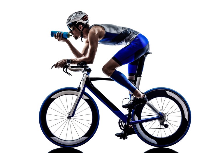 Man in cycling uniform drinking from bottle on bicycle