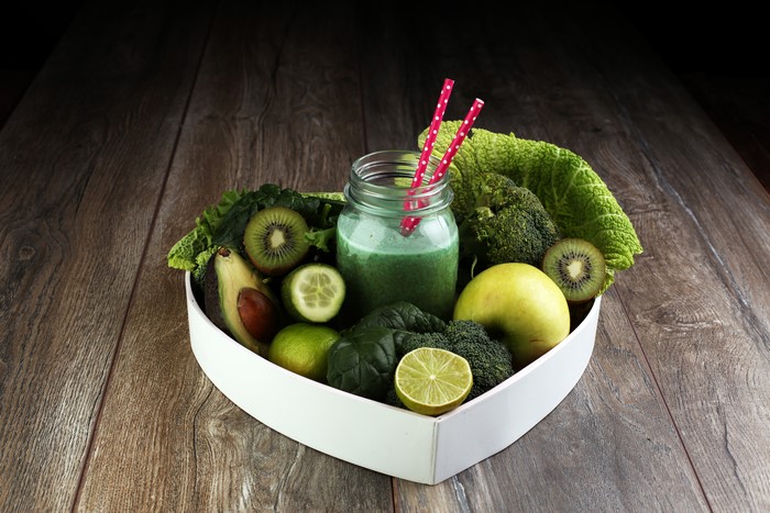 Green smoothie with fruits and vegetables in a heart-shaped bowl