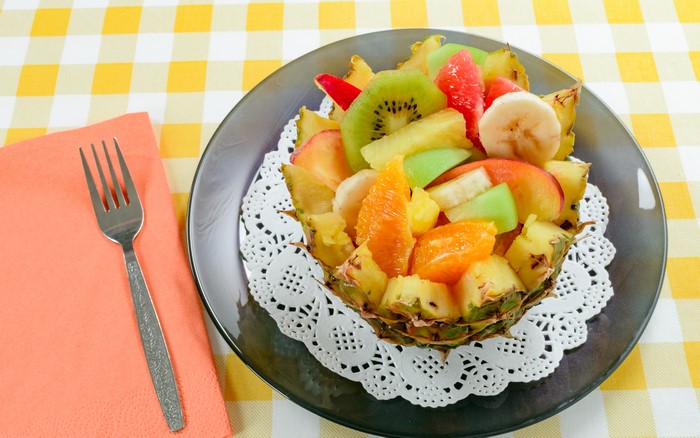 Fruit salad in pineapple bowl on plate with fork