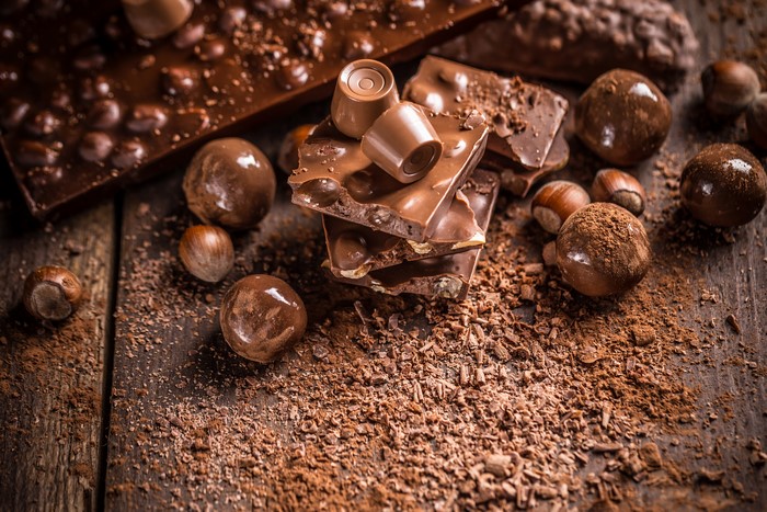 Chocolate bars, candies, hazelnuts, and cocoa powder on wood