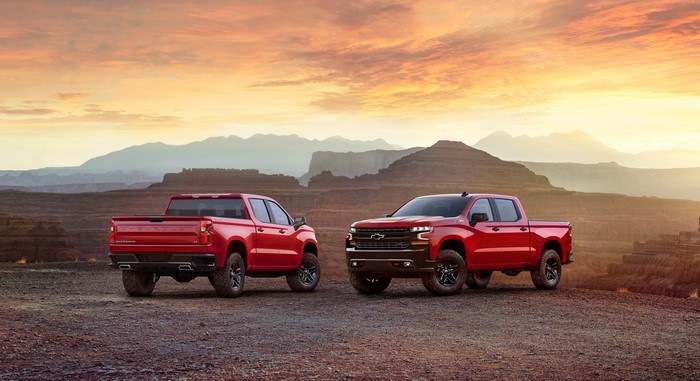 Two red Chevrolet Silverado pickup trucks in a desert landscape