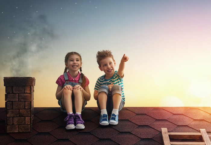 Children sitting on a roof at sunset