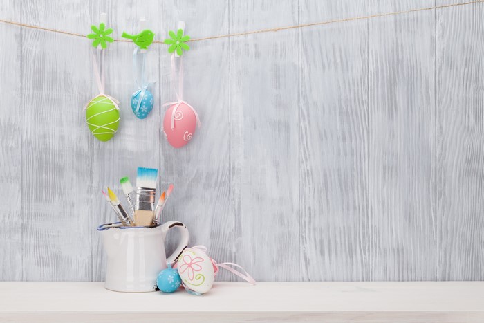Easter eggs and paintbrushes on a wooden wall