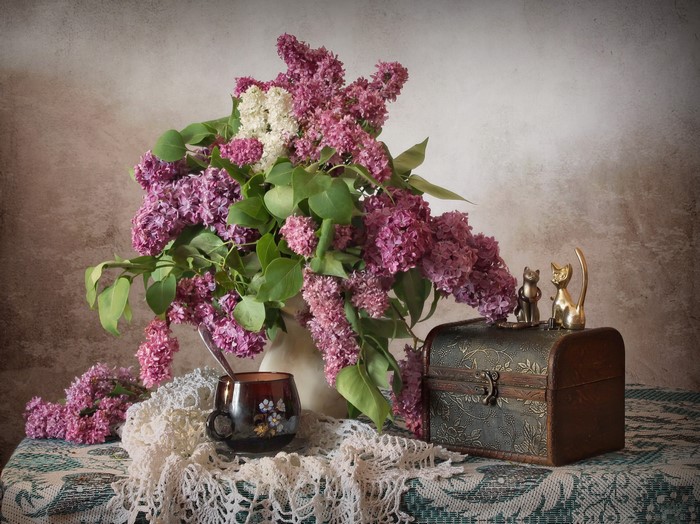 Still-life with lilac bouquet, cup, and cat figurines