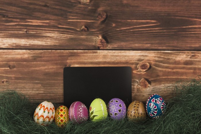 Easter Eggs on Grass with Wooden Background and Chalkboard