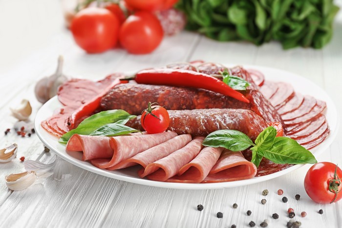 Plate of sliced meats with tomatoes and chili peppers