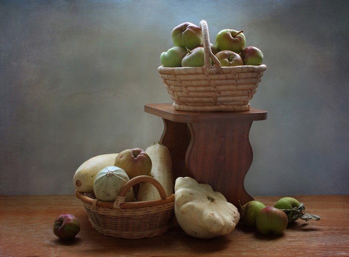 Apples and vegetables in wicker baskets on a wooden table