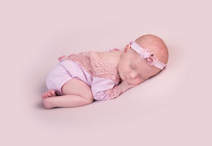 Newborn baby sleeping on pink background