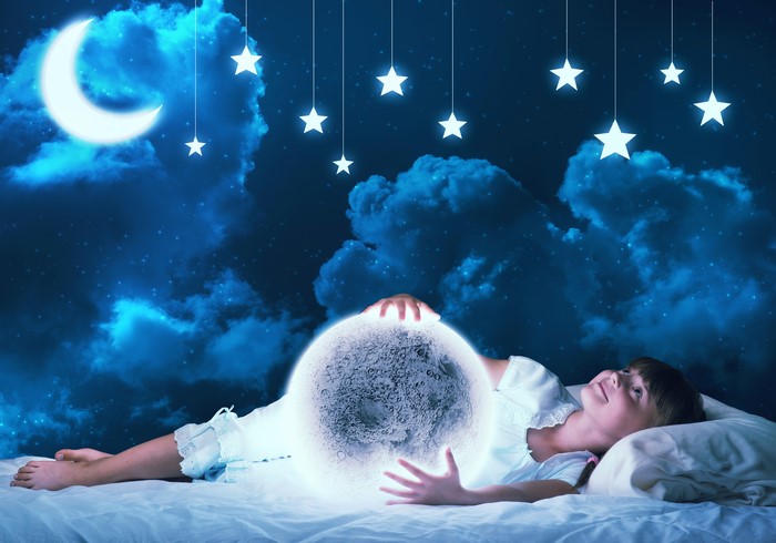 Little girl holding the moon in a starry night sky