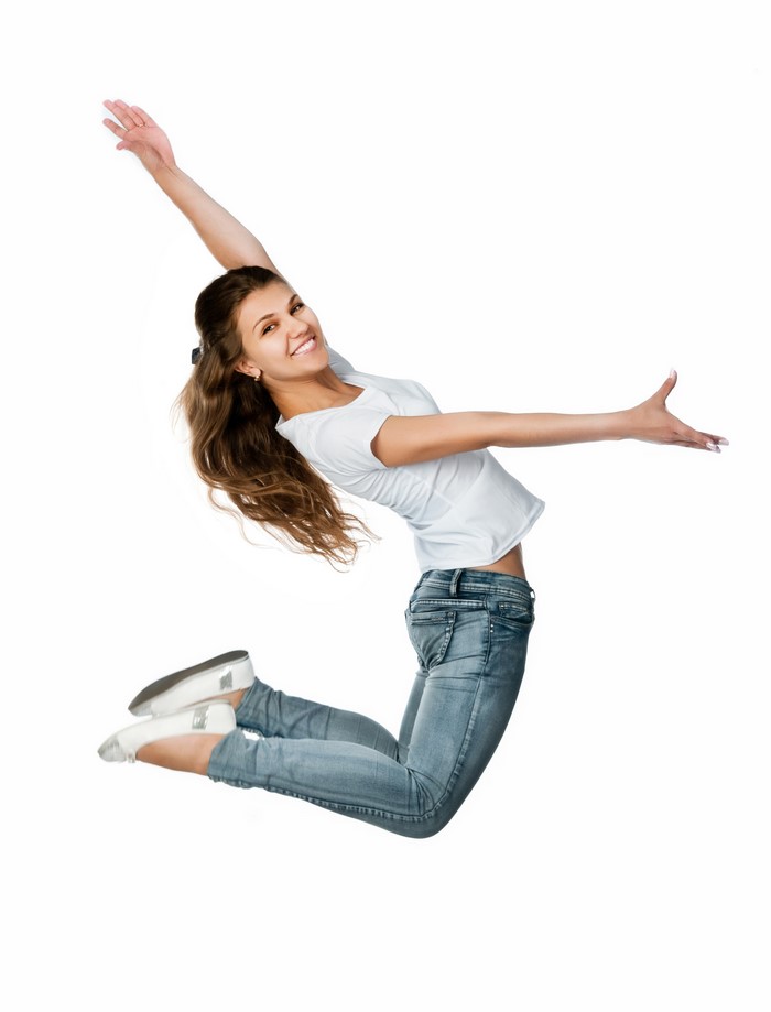 Young woman in jeans jumping with arms outstretched