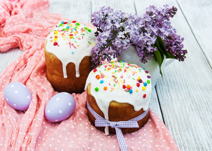 Easter Kulich cakes with lilac and eggs on wood
