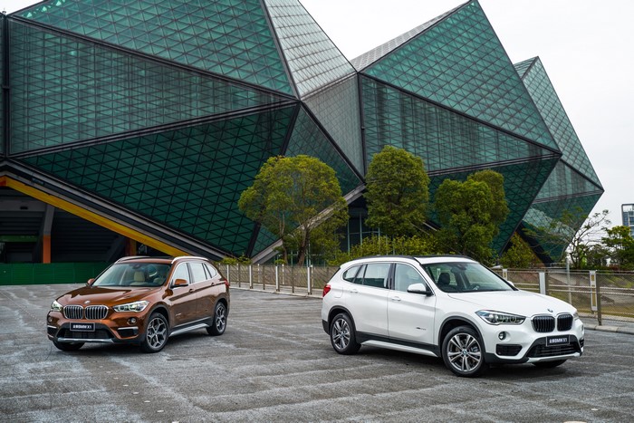 Two BMW X1 cars in front of a modern building