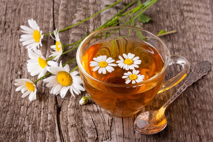 Chamomile tea in a cup with chamomile flowers and a spoon