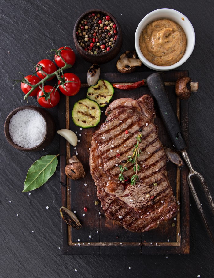 Grilled steak with vegetables and spices on a cutting board