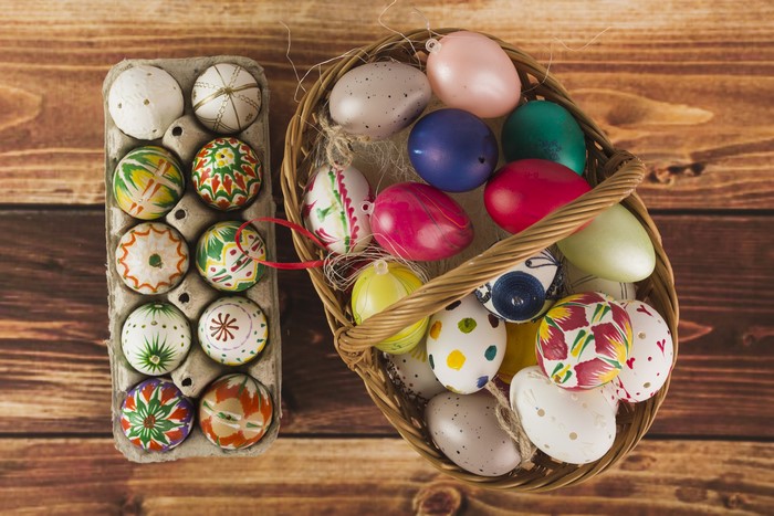 Easter eggs in a basket and carton on wood