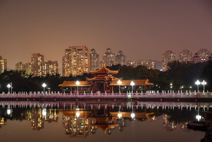 Night view of a Chinese pavilion and city skyline reflected in water