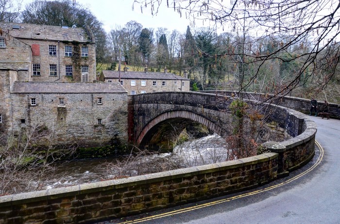 Stone bridge over a river with old buildings in Aysgarth, England