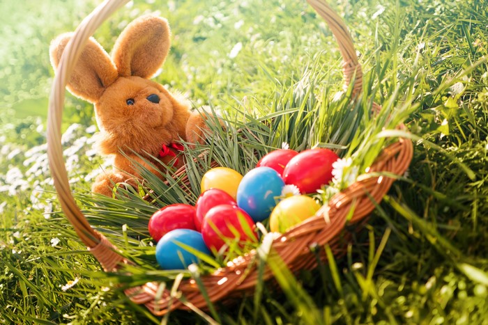 Easter basket with bunny and colorful eggs in grass