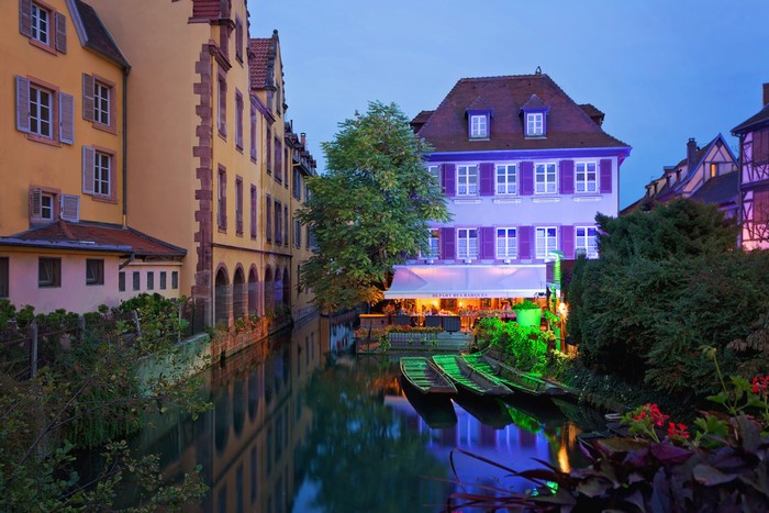 Colmar, France canal with boats and illuminated buildings at dusk