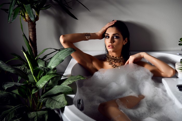 Woman in bathtub with jewelry and plants