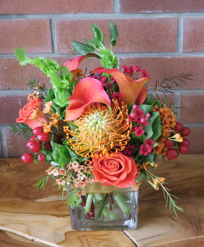 Orange and pink floral arrangement in a glass vase