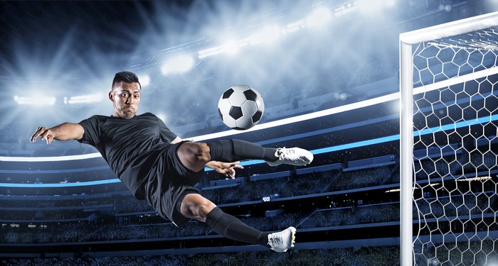 Soccer player kicking a ball in a stadium