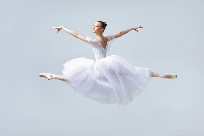 Ballerina in white dress performing a jump