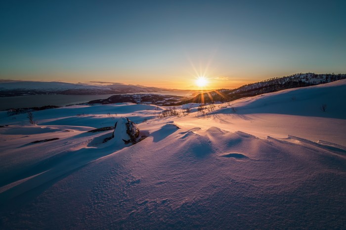 Winter sunset over snowy mountains and a fjord