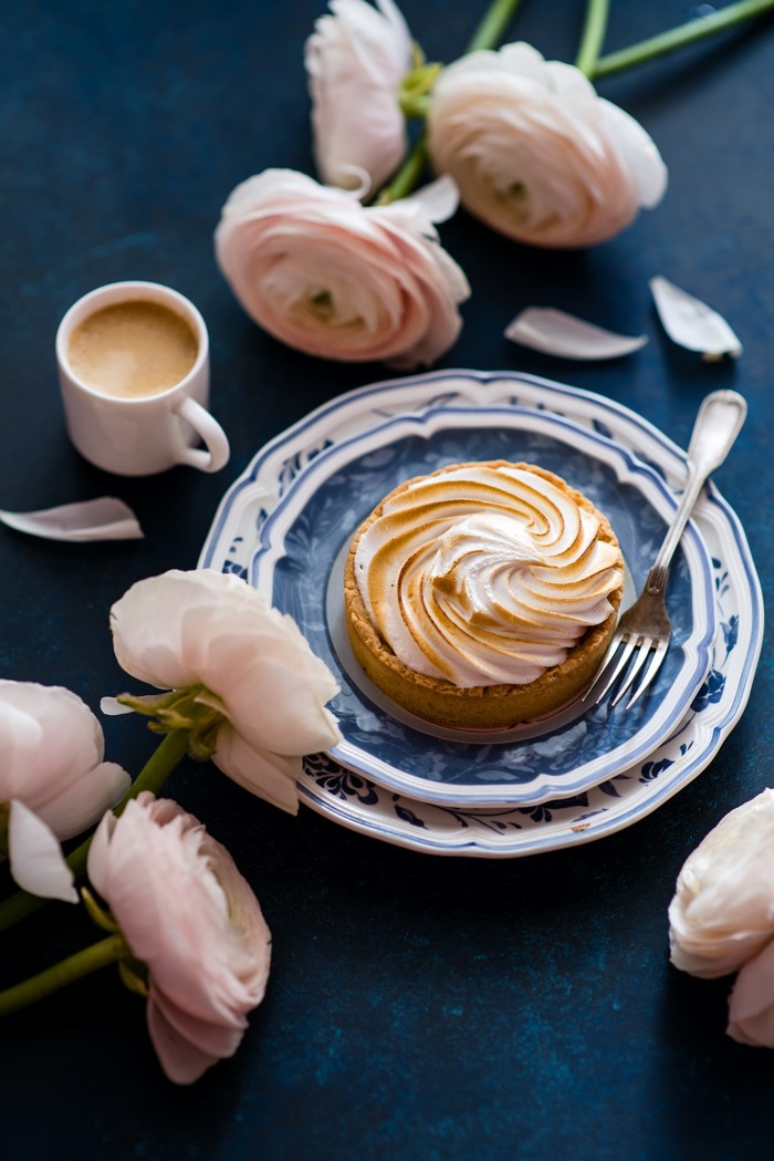 Lemon meringue tart with coffee and ranunculus flowers