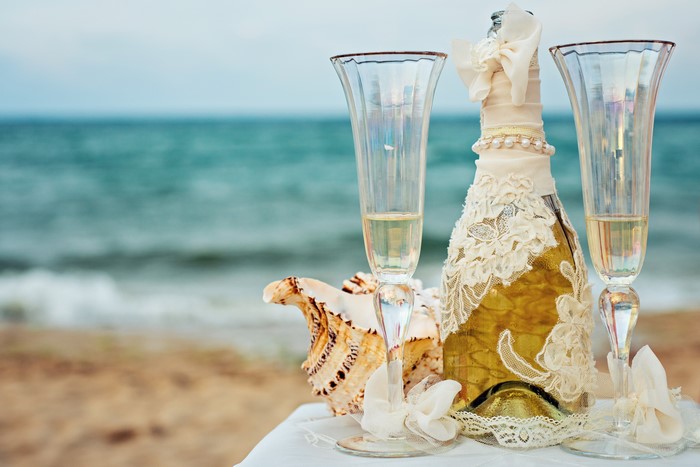 Champagne bottle and glasses on beach