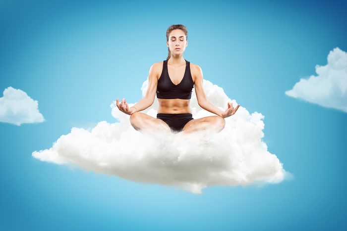 Woman meditating on a cloud in the sky