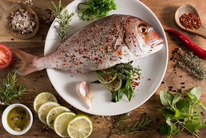 Whole Fish Seasoned with Spices on a Plate with Ingredients
