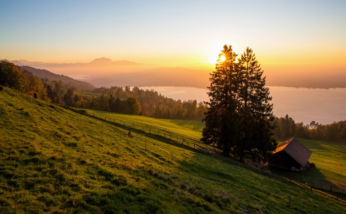 Sunset over a lake with mountains and a barn