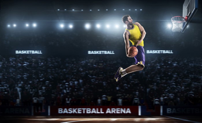 Basketball player jumping with ball in arena