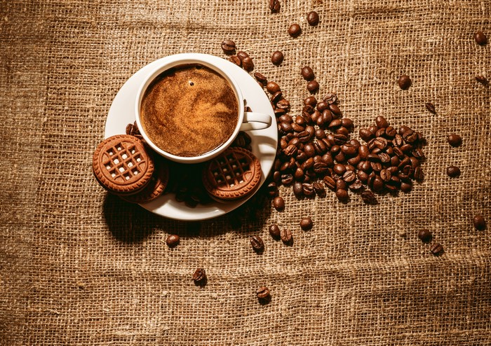 Coffee cup with cookies and coffee beans on burlap