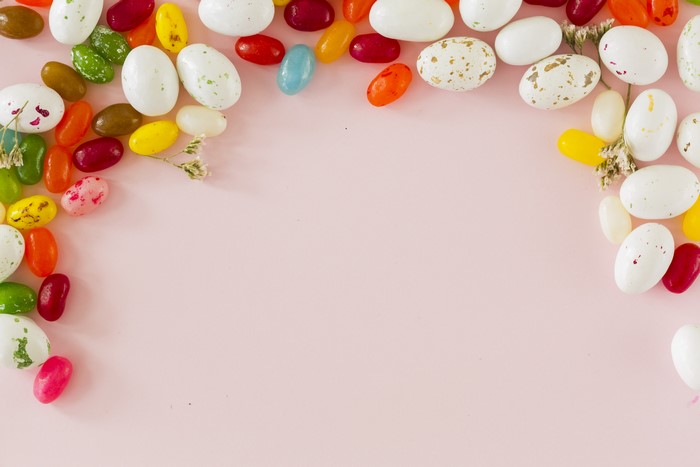 Easter candies and dried flowers on a pink background