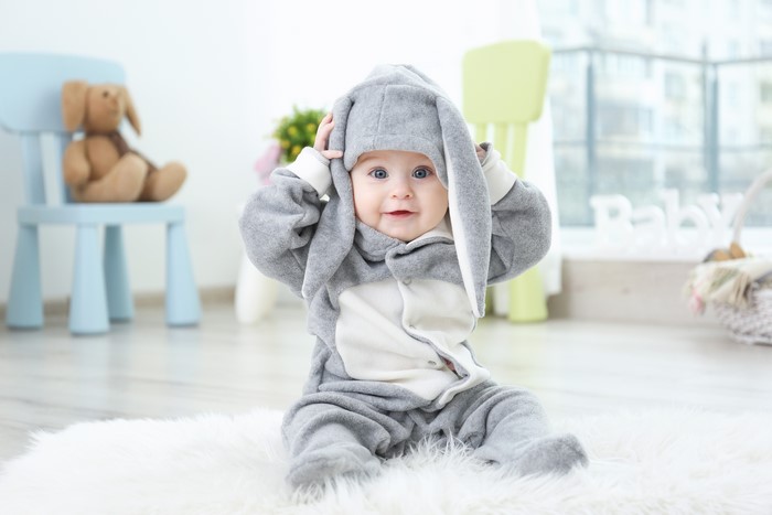 Baby in a bunny costume sitting on a rug