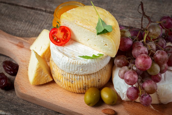 Cheese, Olives, Grapes, and Tomatoes on a Cutting Board
