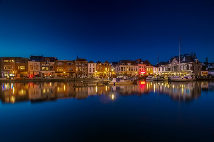 Cityscape with canal and boats at night in Leiden, Netherlands
