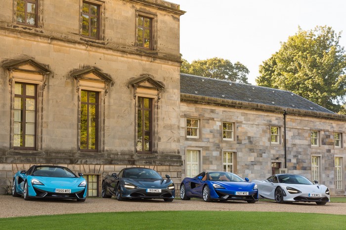 Four McLaren sports cars parked in front of a stone building