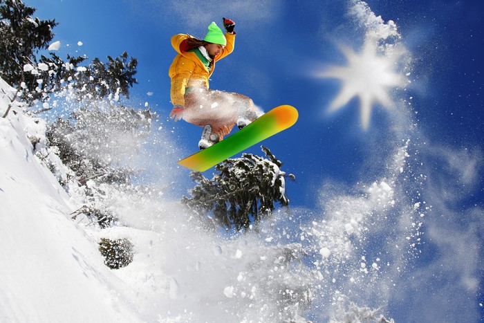 Snowboarder jumping in the air with snow spray